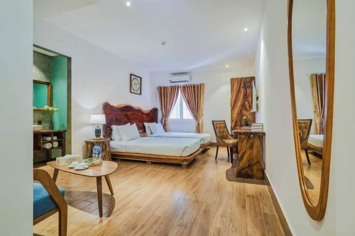 A hotel room with a bed, a desk, a chair, and a mirror.