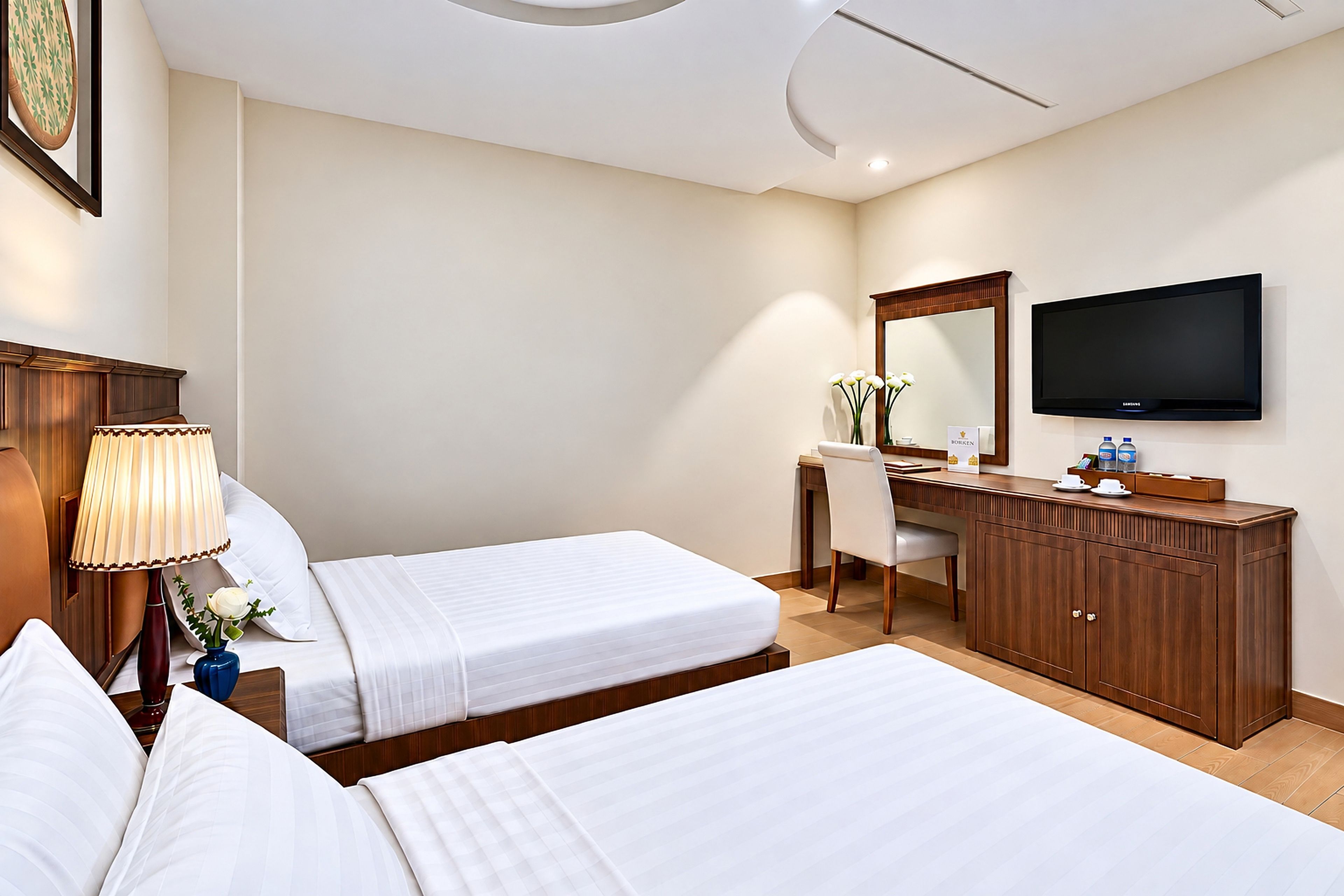 Una habitación de hotel con dos camas, un escritorio, un televisor y un espejo.