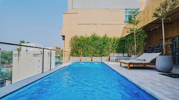 Una piscina al aire libre, sillones reclinables de piscina