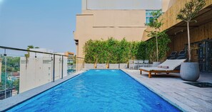 A rooftop pool with a wooden deck, lounge chairs, and a view of the cityscape. - Sky Gem Hotel - Ben Thanh (Ho Chi Minh City)