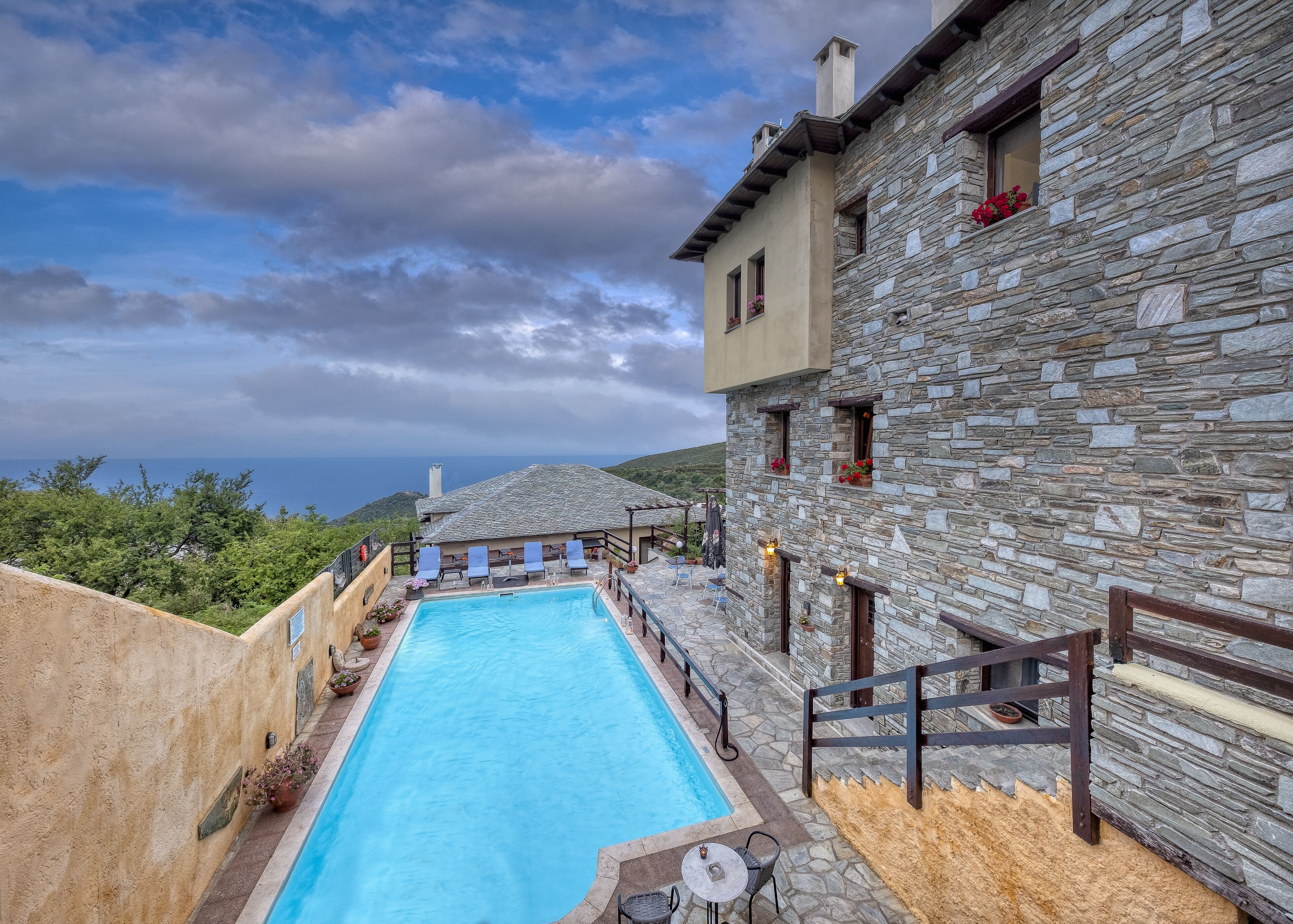 Un bâtiment en pierre doté d’une piscine, d’un espace extérieur aménagé et offrant une vue sur la mer.