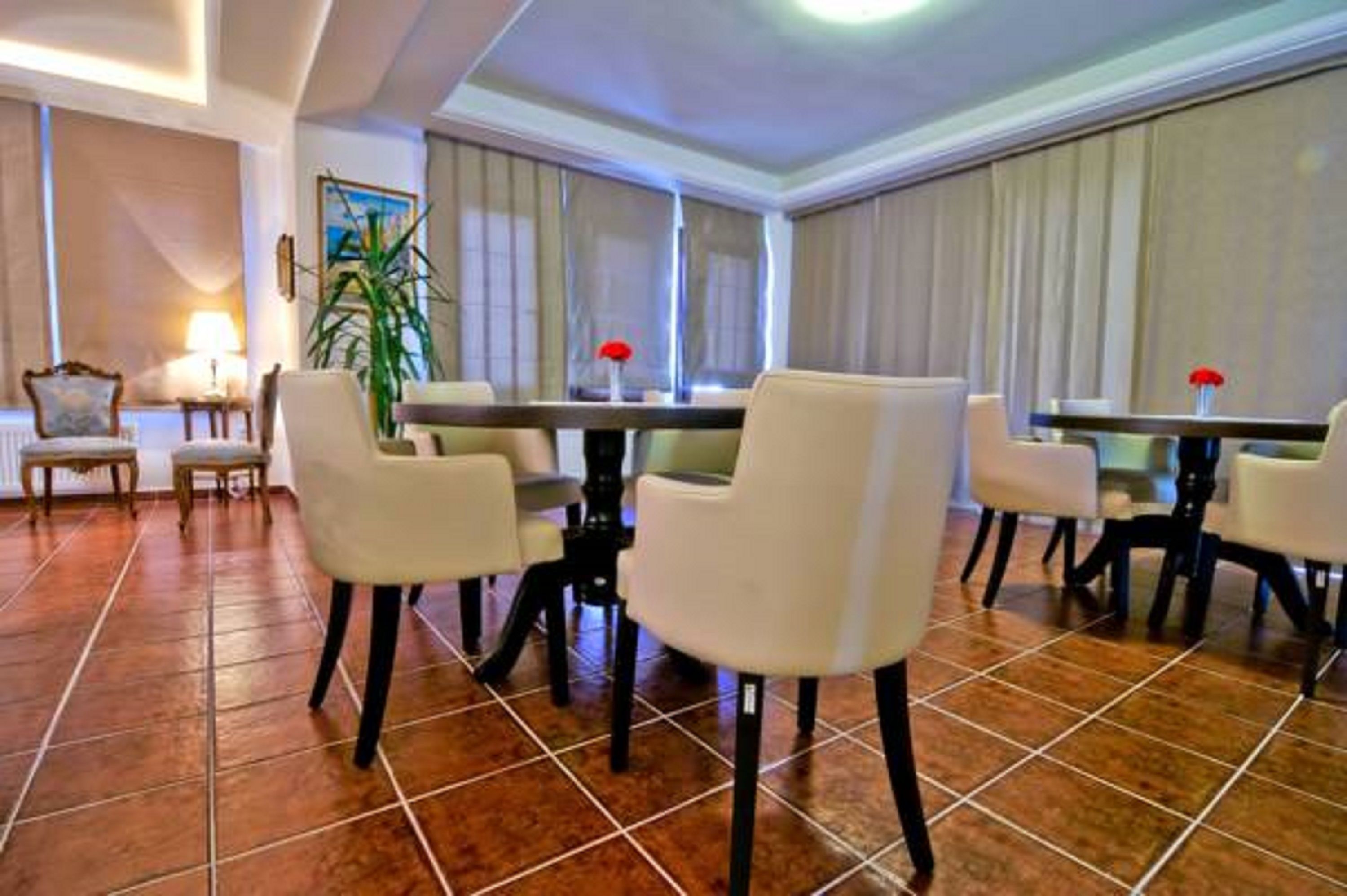 Un espace de restauration d’hôtel avec une longue table, plusieurs chaises et une plante en pot.