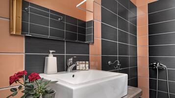 Een moderne badkamer met een groot wit bad, een houten wastafelmeubel, een spiegel en een douchegedeelte.
