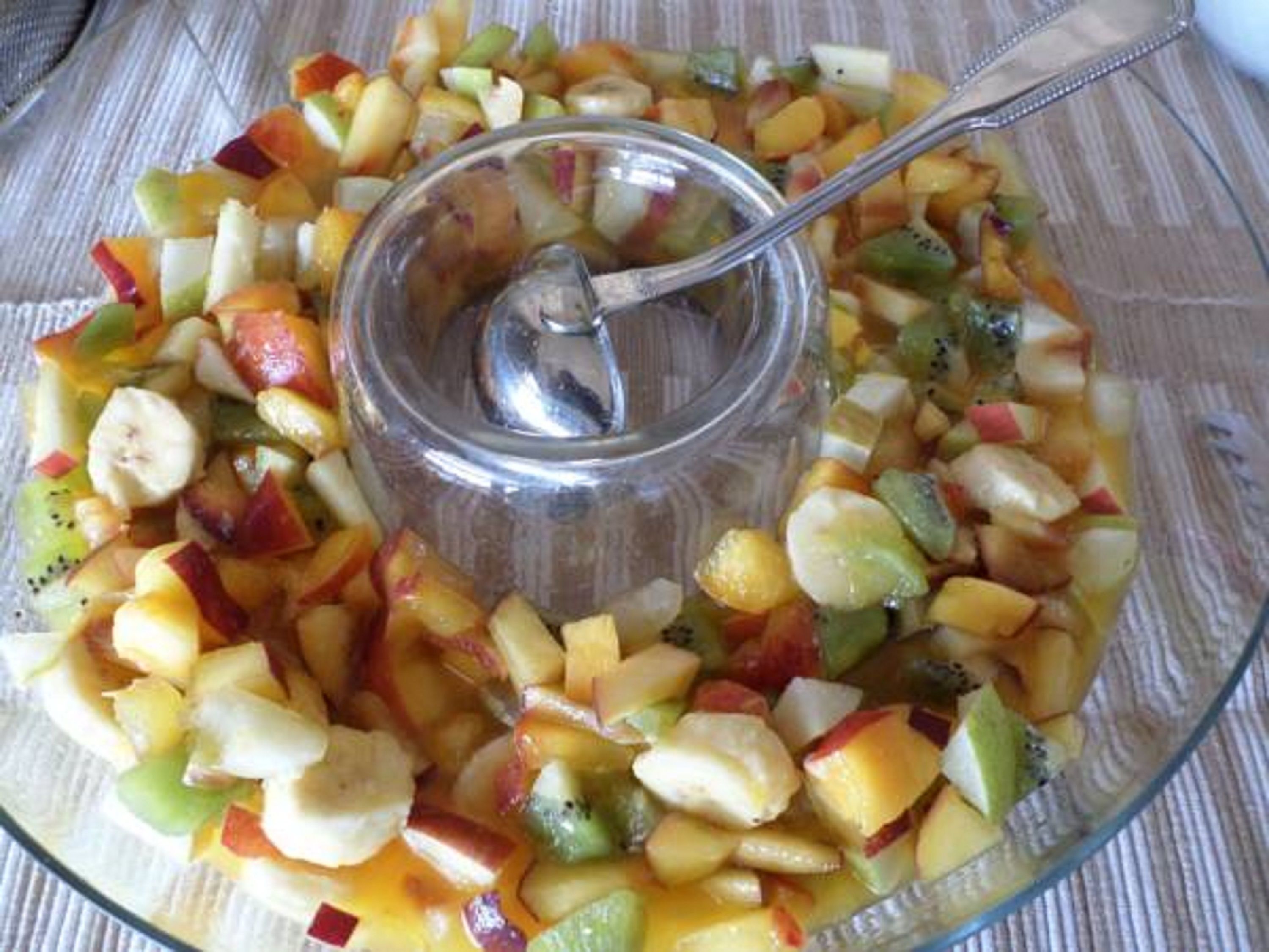 A glass bowl filled with diced fruits and a spoon.