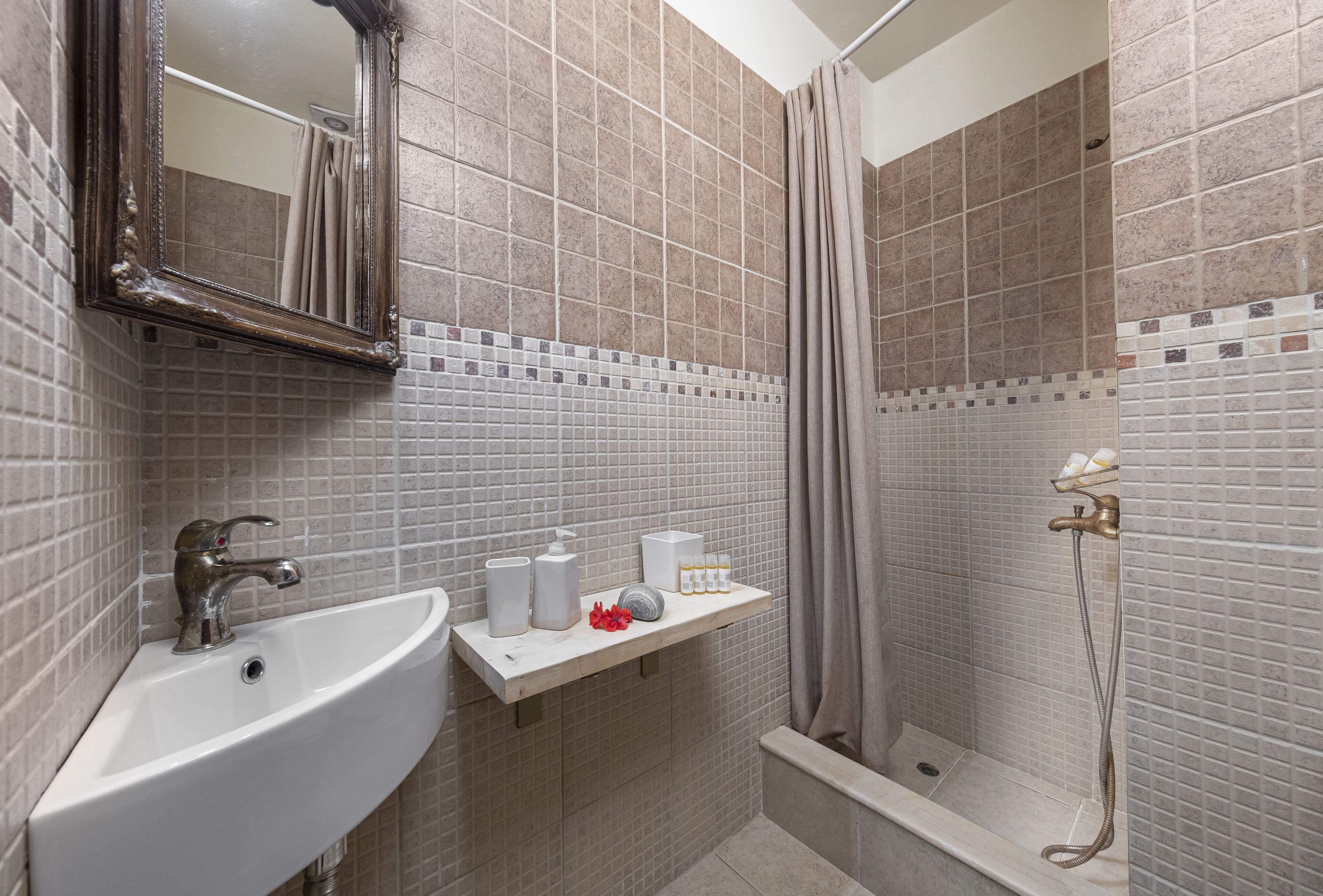 Un baño con lavamanos, espejo, ducha y paredes de azulejos.
