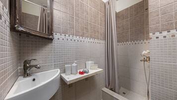 Un baño con lavamanos, espejo, ducha y paredes de azulejos.
