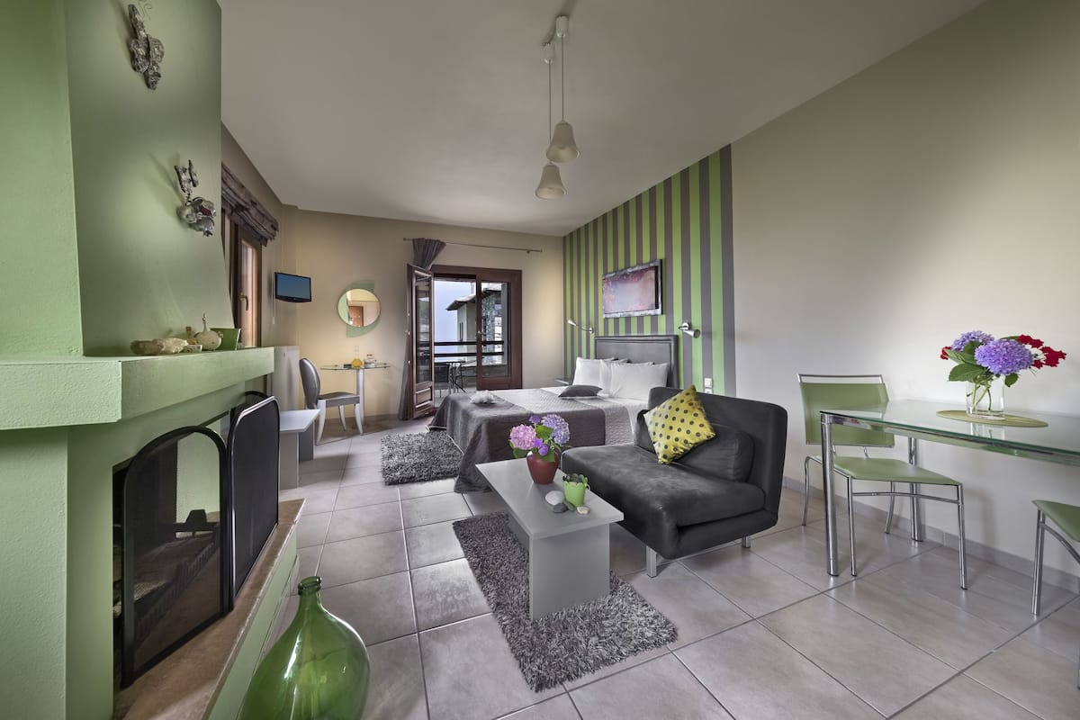 Un salon moderne avec un canapé, une table basse et des fauteuils. On y trouve une cheminée, un téléviseur et un coin repas avec une table en verre.