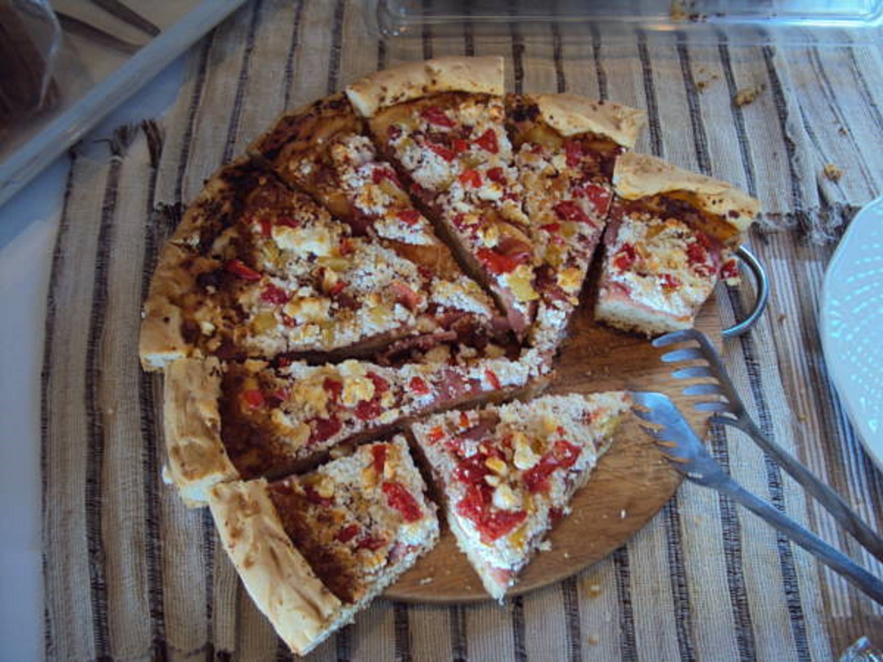Una pizza sobre una tabla de madera, con un cuchillo y un tenedor a un lado.