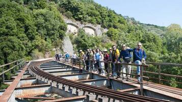 A group of people standing on a railway bridge with a mountainous backdrop.