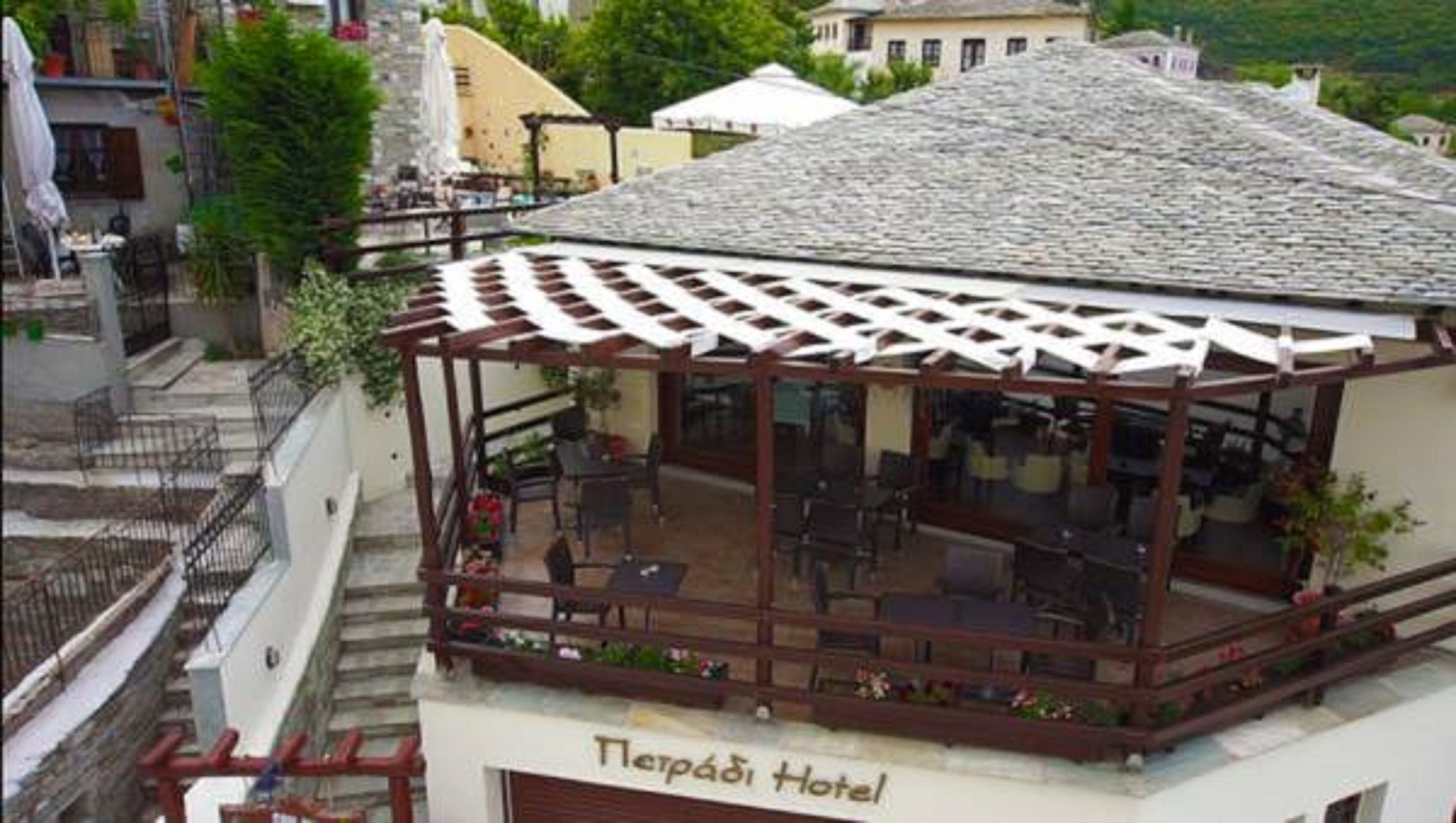 Een hotel met een overdekte buiten zitplaats, een stenen dak en een bordje met de tekst 'Petrabi Hotel'.
