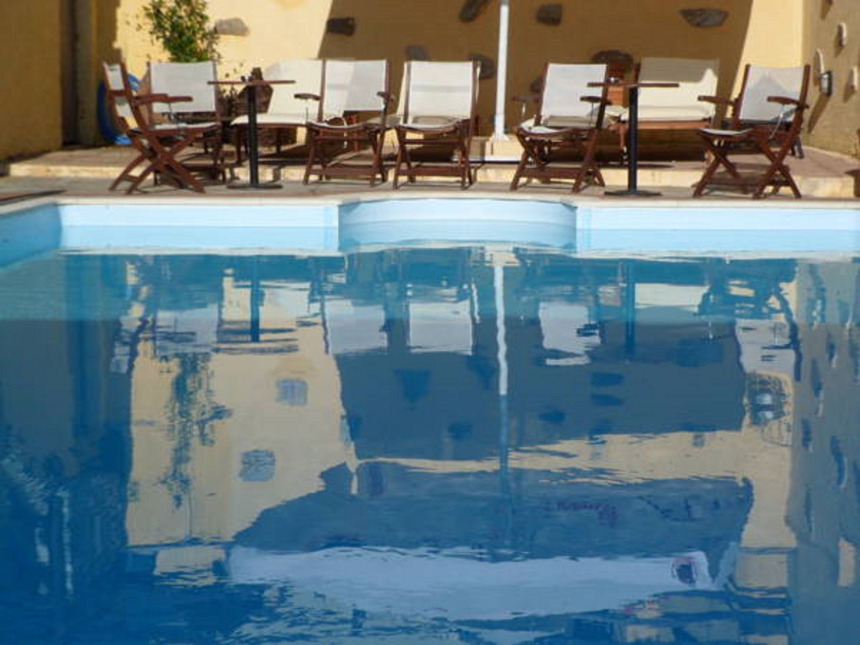A swimming pool with lounge chairs and a sunbed.