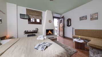 A bedroom with a large bed, a fireplace, a television, and a bench.