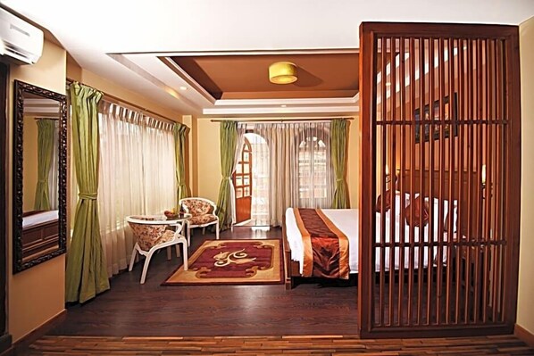 A hotel room with a bed, a desk, a chair, a mirror, and a window with curtains. - Quality Inn Woodside (Woodside)