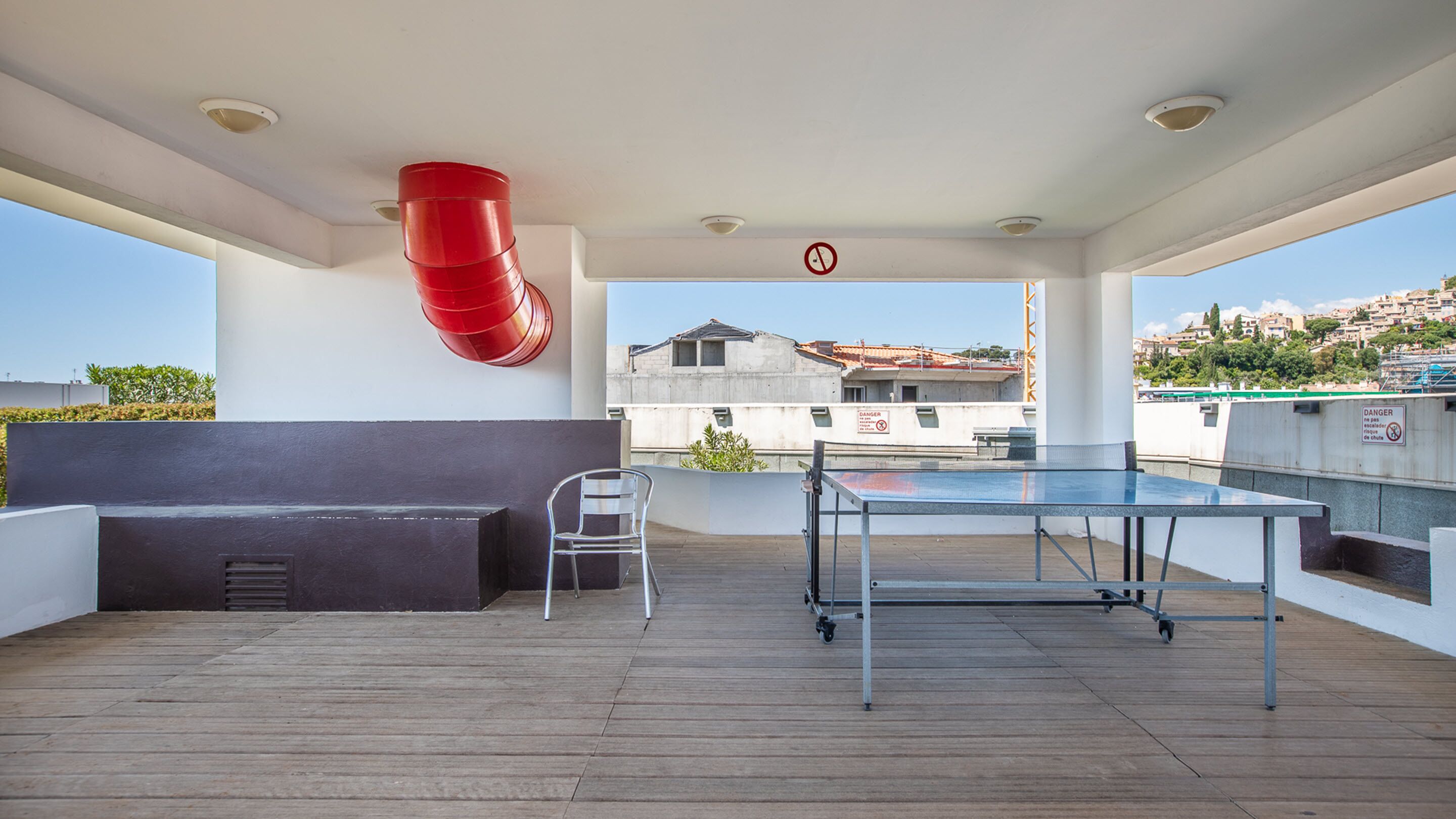Terraza en la azotea con mesa de ping pong, zona de estar y manguera contra incendios roja.