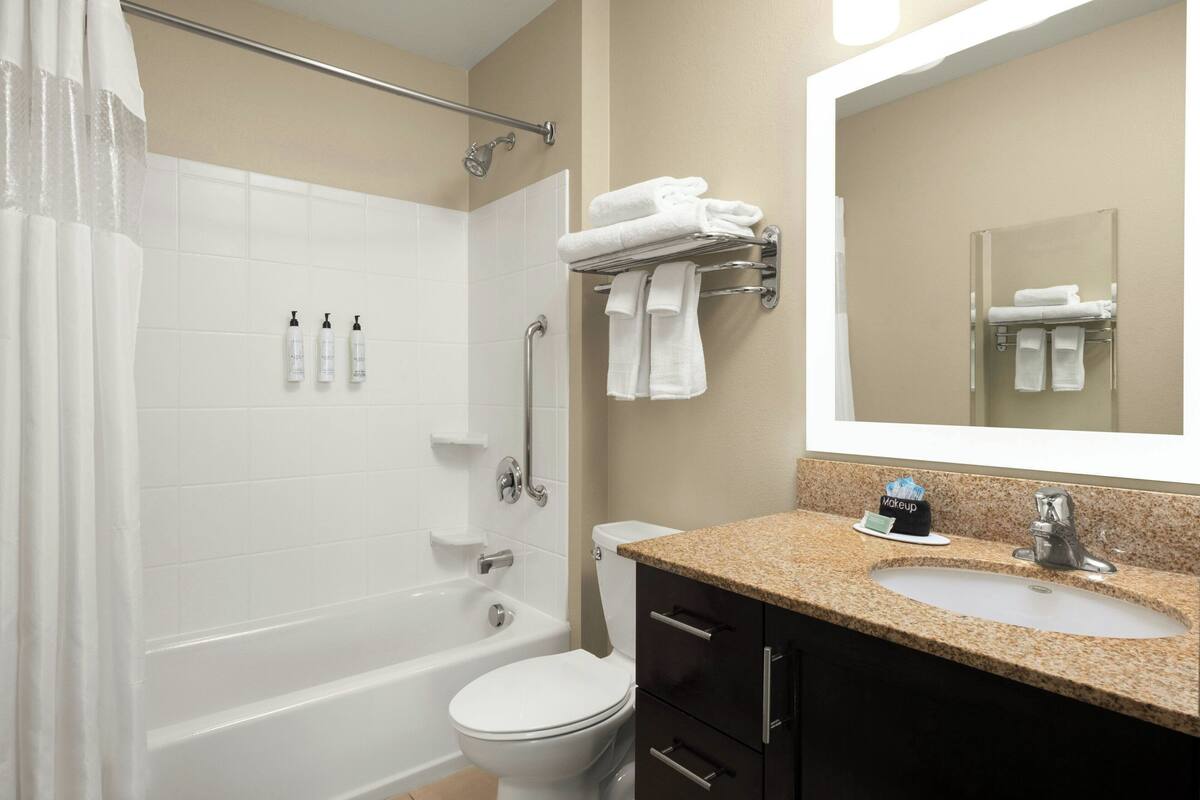 A bathroom with a bathtub, toilet, sink, and a mirror.