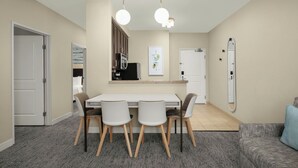 Un espacio habitable compacto con zona de comedor, kitchenette y un espejo grande.