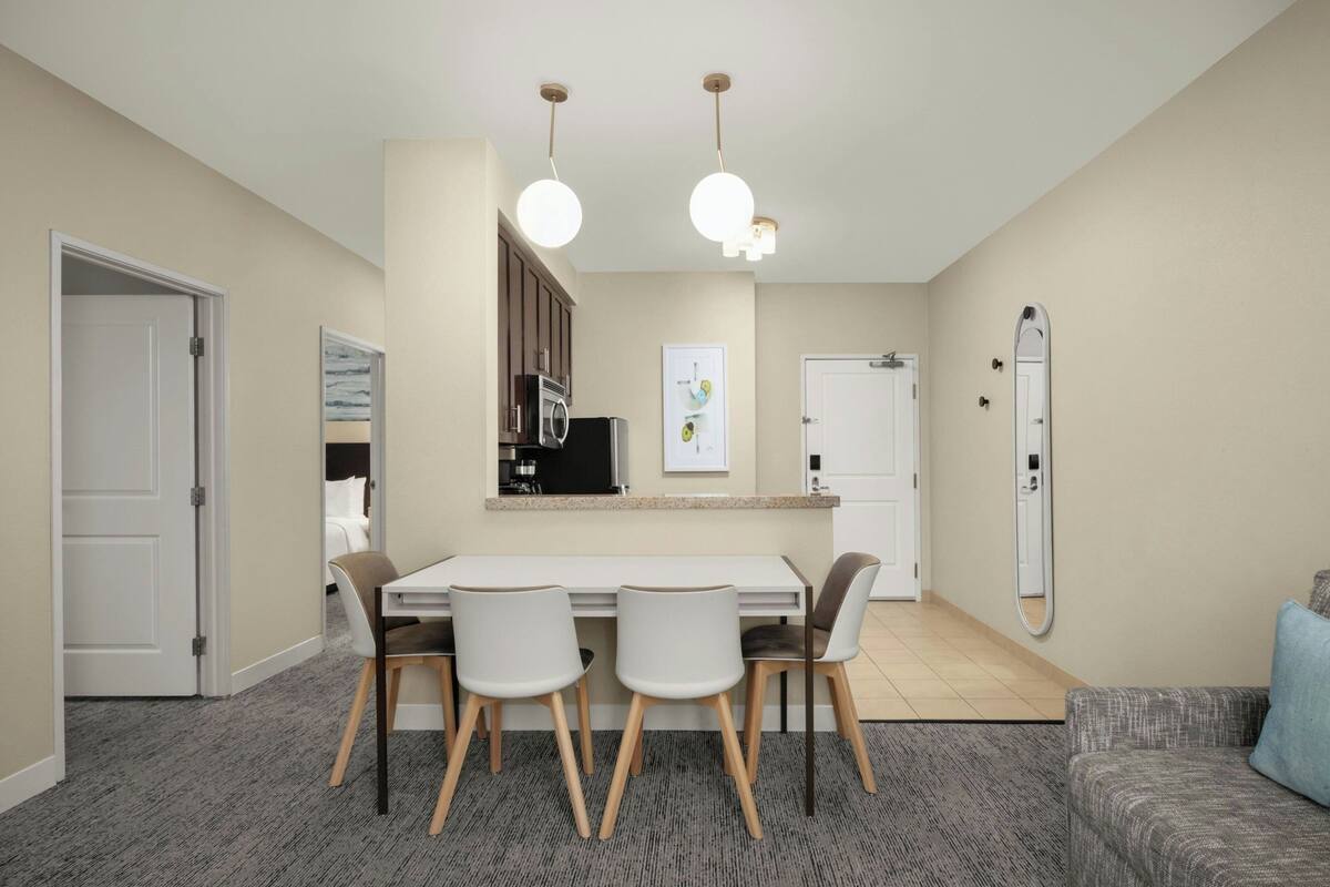 A compact living space with a dining area, kitchenette, and a large mirror.