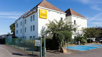 A white building with a sign reading "Premiere Classe" and a fenced parking area.