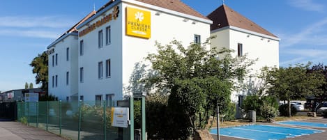 A white building with a sign reading "Premiere Classe" and a fenced parking area.