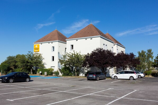 A parking lot with several cars, a building with a sign, and trees.