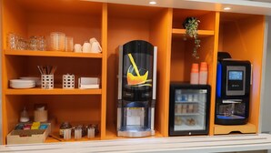 A coffee station with a coffee machine, a refrigerator, and shelves with cups and utensils. - Première Classe Nantes Ouest - Saint Herblain (Saint-Herblain)