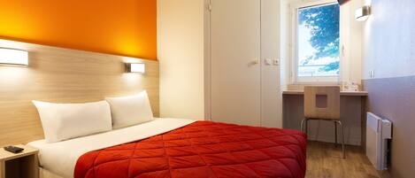Una habitación de hotel con cama, escritorio y silla.