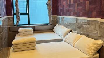 A hotel room with a large bed, a window with curtains, and a view of the city.