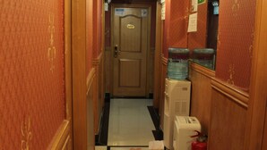 A hotel hallway with a checkered floor, a fire extinguisher, and a water dispenser. - Venetian Hostel (Kowloon)