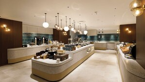 A modern kitchen with a central island, pendant lighting, and a coffee station.