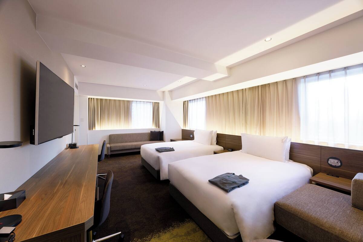 Een hotelkamer met twee bedden, een bureau en een televisie.