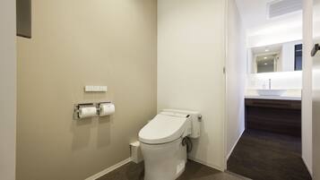 Un baño pequeño y moderno con inodoro blanco, dispensador de toallas y zona de ducha visible.