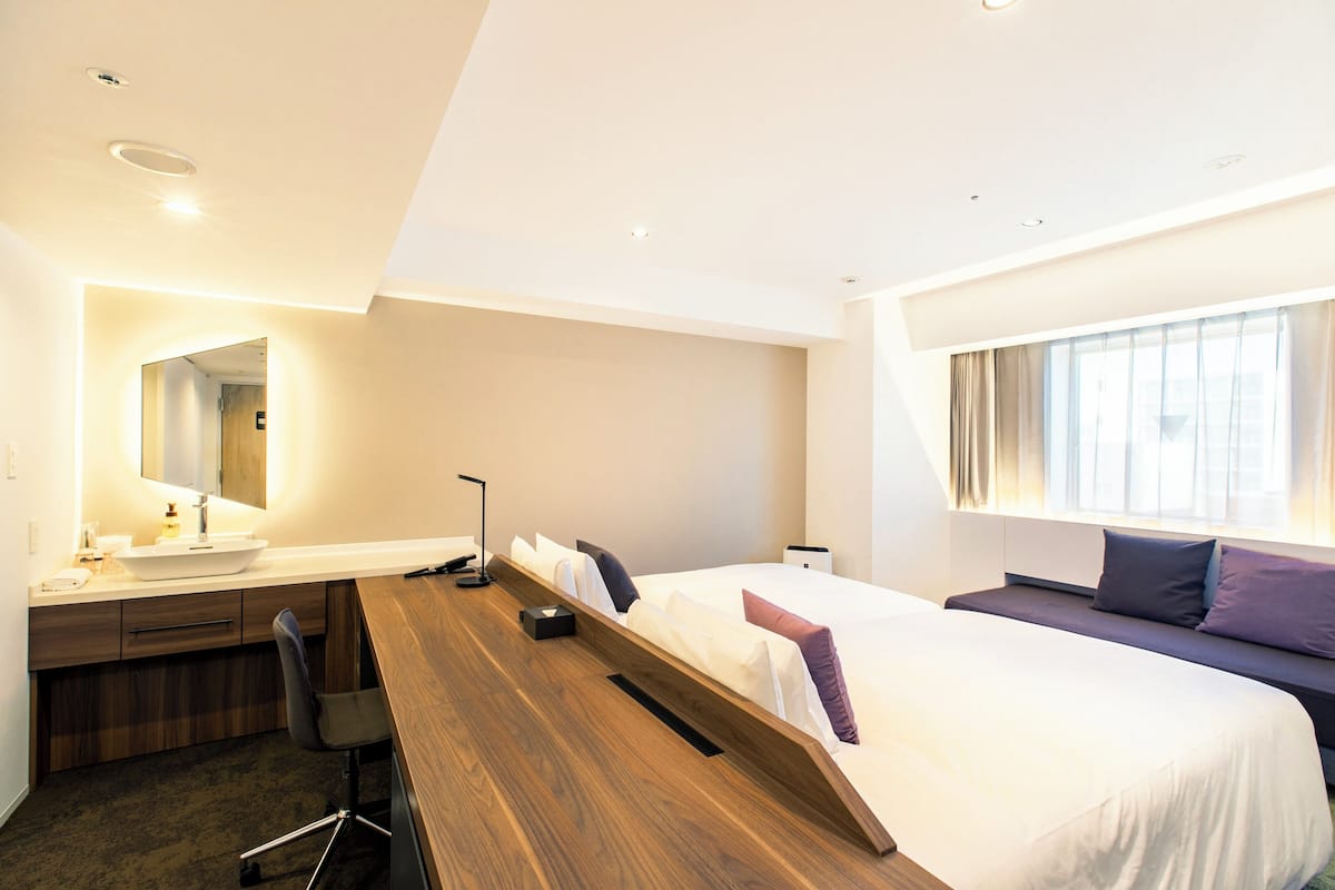 Een moderne hotelkamer met een houten bureau, een bed met uitzicht, een grote spiegel en een nachtkastje.