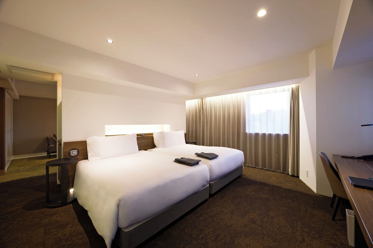 Een hotelkamer met een groot bed, een bureau en een raam met gordijnen.