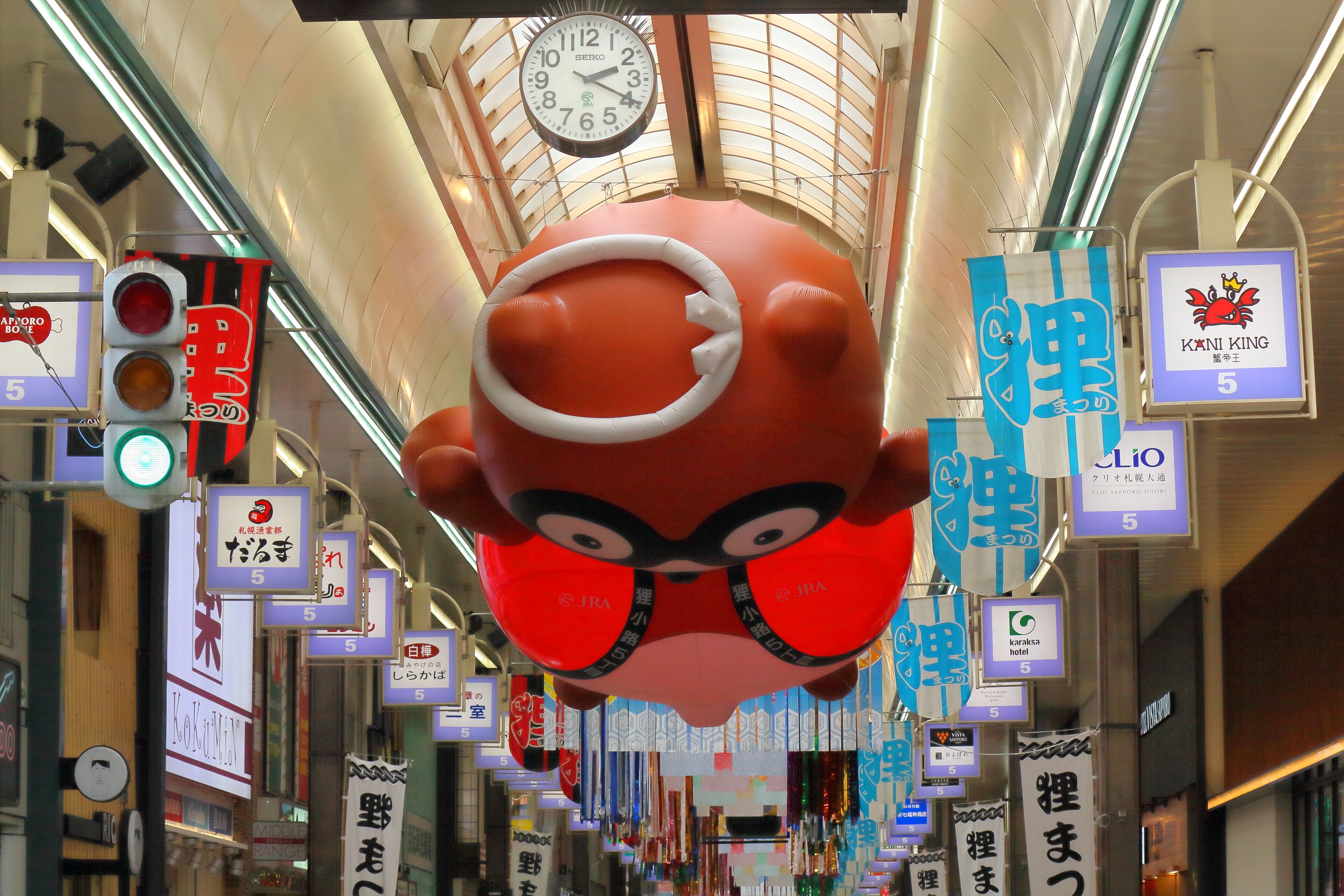 A corridor with various signs and a large red character decoration.