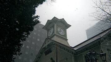 A building with a clock tower, featuring a traditional clock face and a pointed roof.