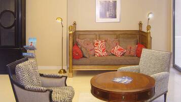 A living room with a sofa, two armchairs, a coffee table, and a framed picture on the wall.