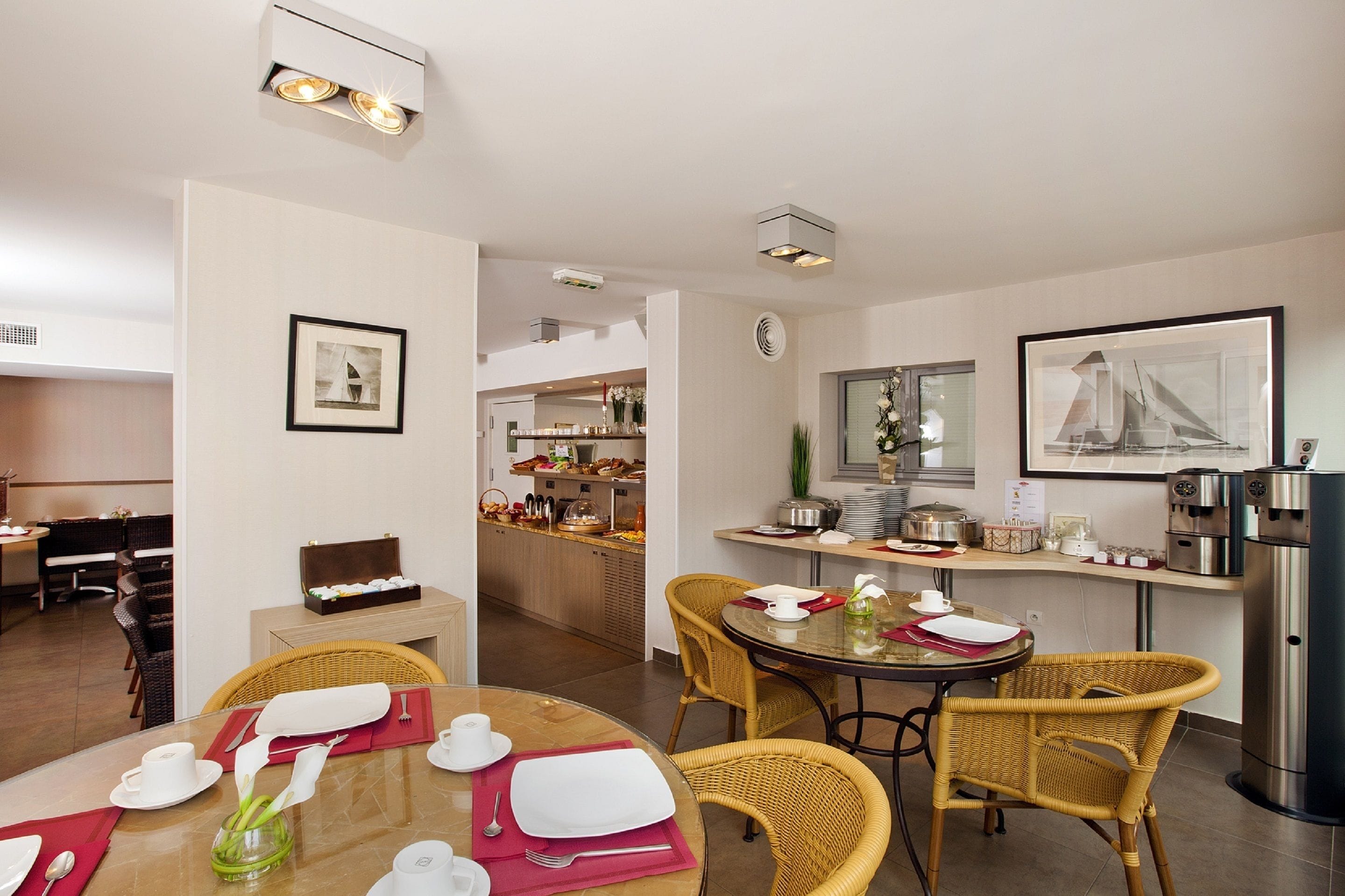 A dining area with wicker chairs, a round table, and a buffet setup in the background.
