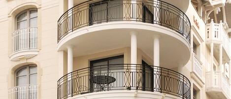 A multi-story building with a curved facade, balconies with wrought iron railings, and classical architectural details.