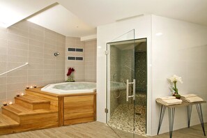 Un baño moderno con una bañera de madera, cabina de ducha de vidrio y una mesita con toallas.