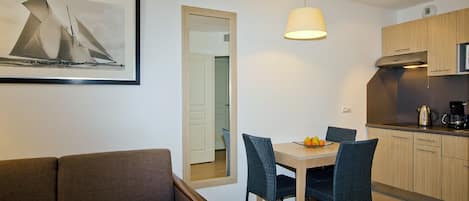 Een moderne keuken met houten kasten, een eettafel met stoelen en een kunstwerk in een lijst aan de muur.