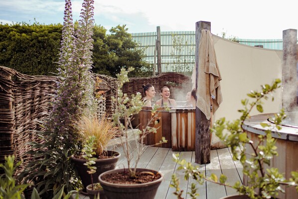 A hot tub area with a wooden deck, potted plants, and a wicker structure. - Bedruthan Hotel and Spa (Newquay)
