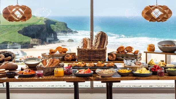 A breakfast buffet with various foods and bread, overlooking a coastal view. - Bedruthan Hotel and Spa (Newquay)