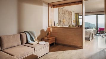 A modern living room with a sofa, a side table, and a lamp. There is a wooden partition with a view of the outside.