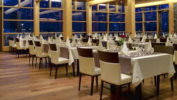 Een restaurant met meerdere tafels gedekt voor diners, grote ramen en een houten vloer.