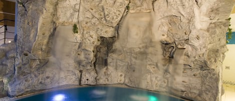 Una piscina con una cascada sobre un fondo rocoso.