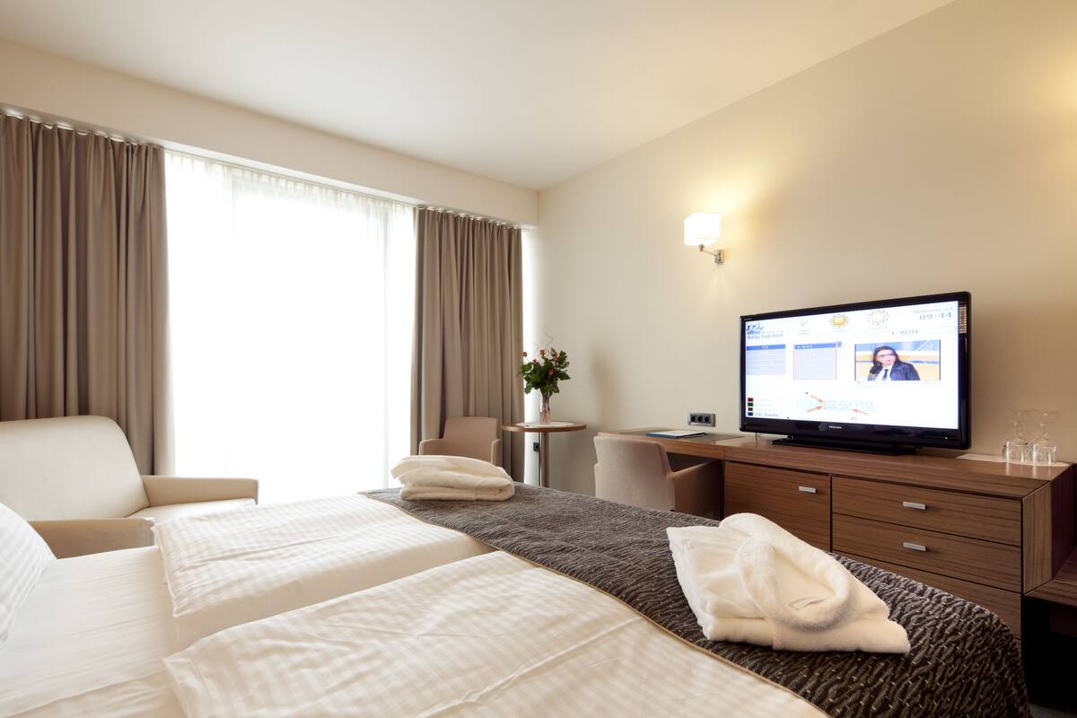 Une chambre d’hôtel avec deux lits, une télévision, un bureau et une chaise.