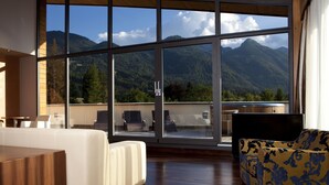 Una habitación moderna con un ventanal amplio que ofrece vistas a la montaña, suelo de madera y un sofá con funda estampada.