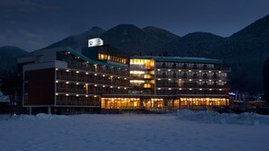 Un hotel de varios pisos con balcones y un telesilla al fondo.