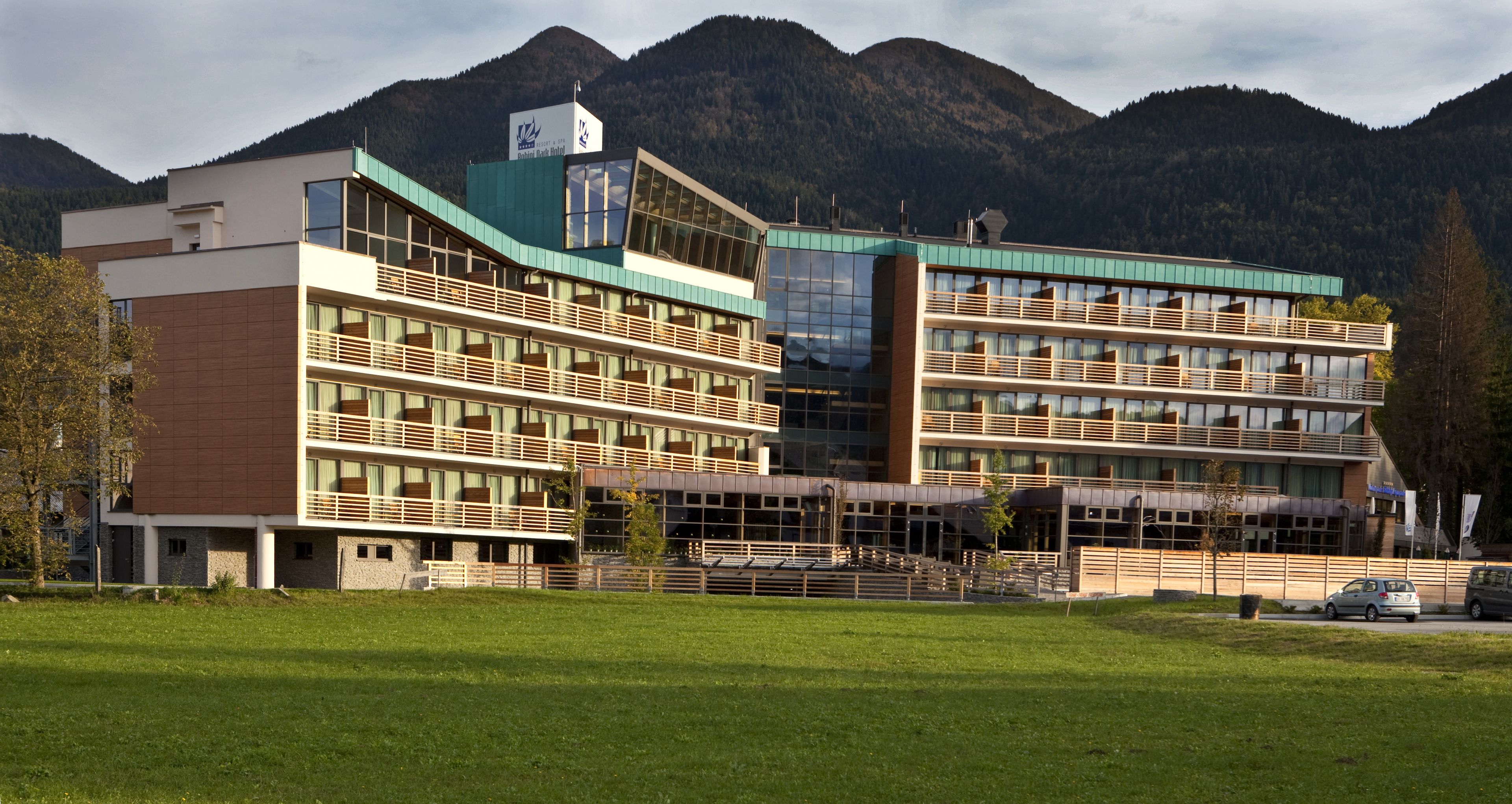 A modern hotel with multiple floors, large windows, and a view of mountains in the background.