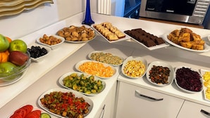 Une table de buffet proposant une variété d’aliments, notamment des fruits, des légumes et des produits de boulangerie.